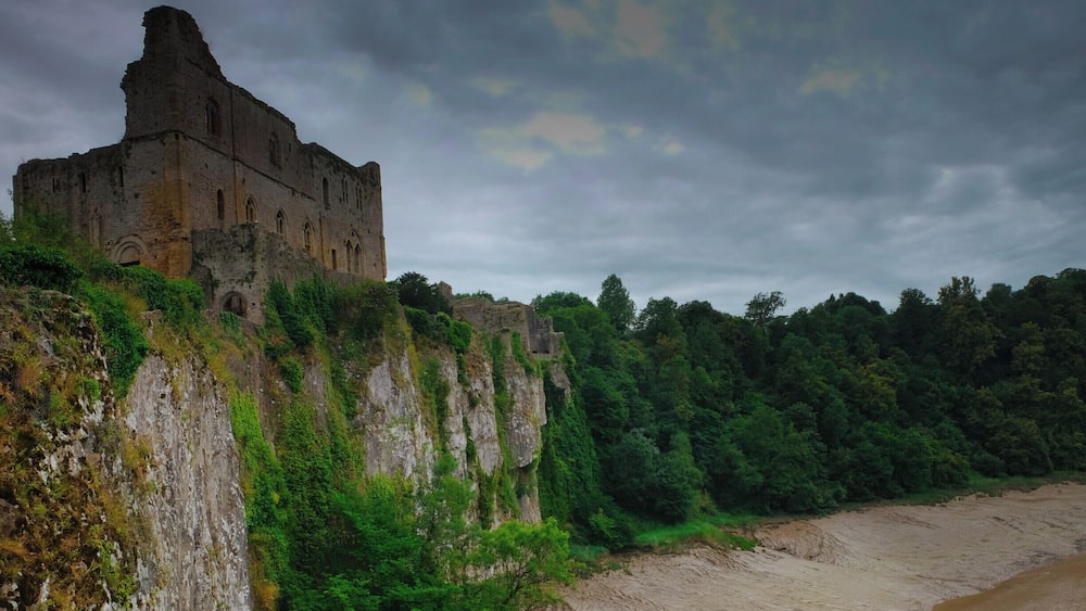 A historic stone building on a cliff overlooking a beach.