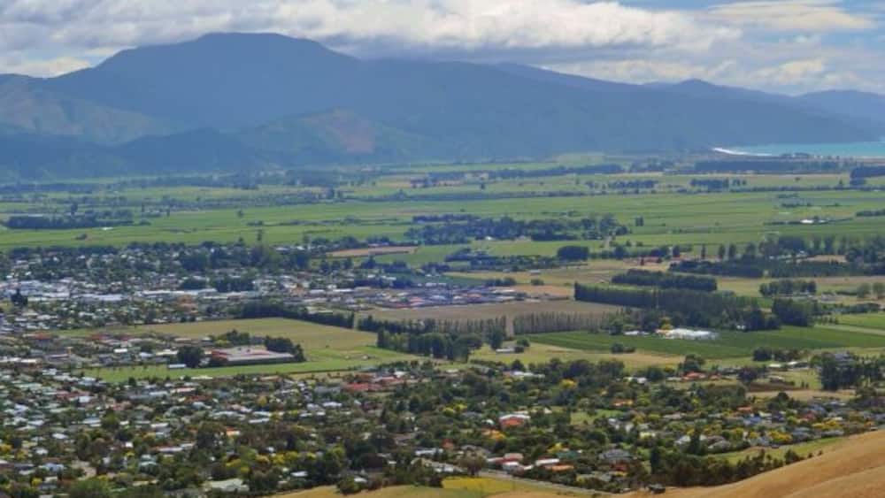 Rolling hills, a town, and distant mountains under a partly cloudy sky.