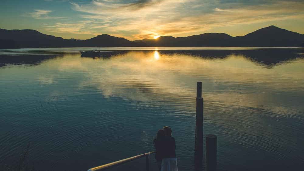 A calm lake with mountains in the background and a sunset.