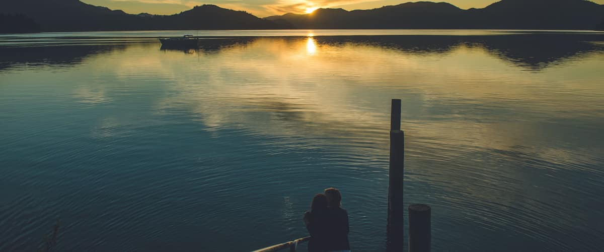 A calm lake with mountains in the background and a sunset.