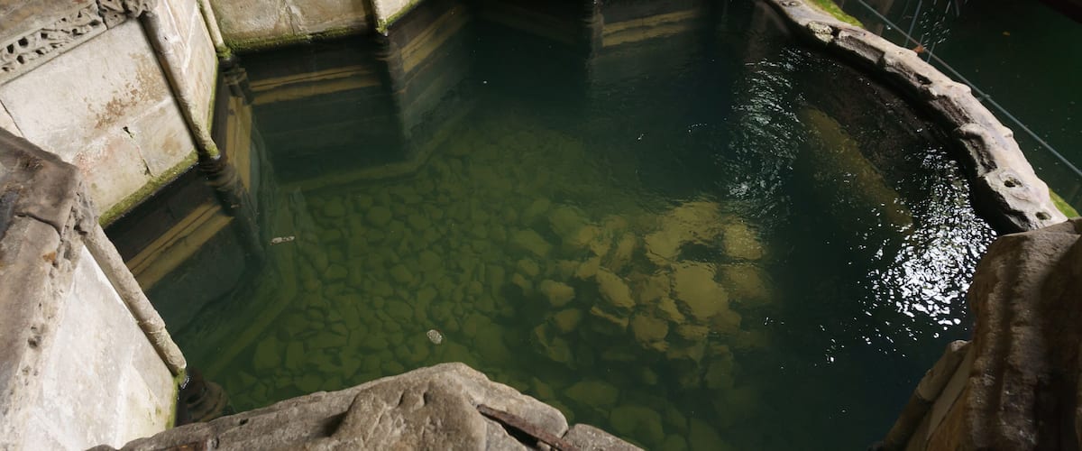 A stone pool with clear water, surrounded by stone walls and steps.