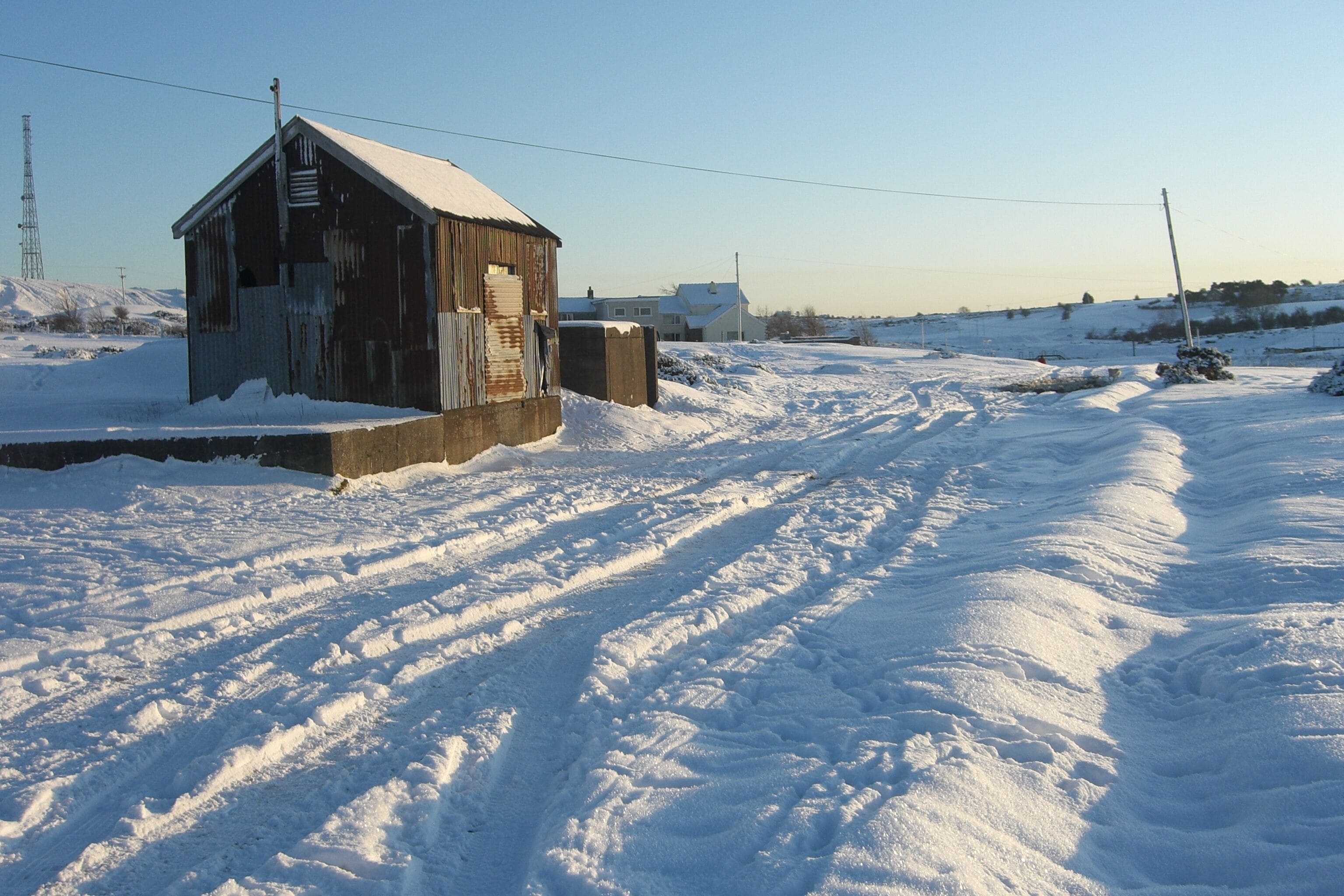 A snow-covered landscape with a wooden structure and a clear sky.