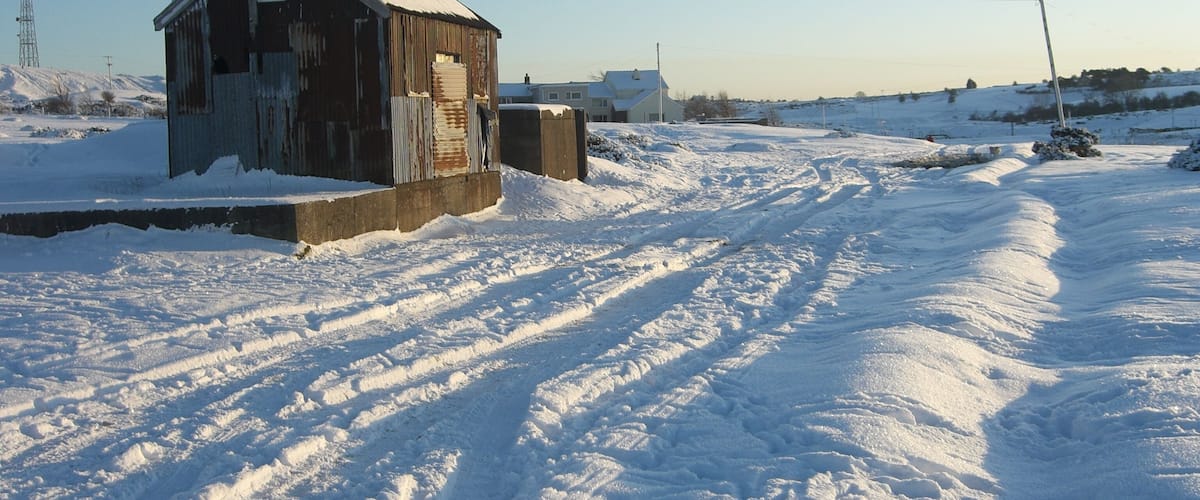 A snow-covered landscape with a wooden structure and a clear sky.