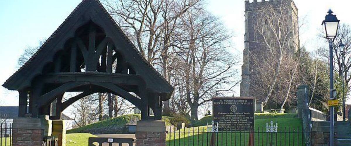 St Woolos Cathedral lychgate and tower The lychgate has two inscriptions. On the left "TO THE GLORY OF GOD THIS LYCHGATE AND WESTERN APPROACH WERE DEDICATED TO THE MEMORY OF DAVID HENRY GRIFFITHS M.A. ARCHDEACON OF MONMOUTH, VICAR OF ST WOOLOS A.D. 1908-1926". On the right "BLESSED IS THE MAN WHOM THOU CHOOSEST AND RECEIVEST UNTO THEE: HE SHALL DWELL IN THY COURTS AND SHALL BE SATISFIED WITH THE PLEASURES OF THY HOUSE".