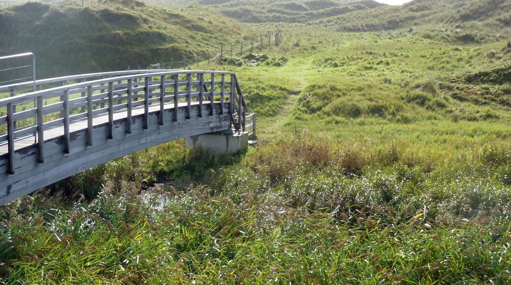 Looking east over a footbridge linking Neath Port Talbot and Bridgend stretches of the Wales Coast Path. The River Kenfig is the boundary, and is also point where the Gower and Swansea Bay section meets the South Wales and Severn Estuary section of the path. The path continues east through Kenfig Sands.