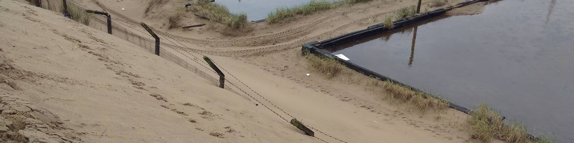 Fencing nearly buried by adjoining sand dunes at the old BP chemicals site near Port Talbot in South Wales.