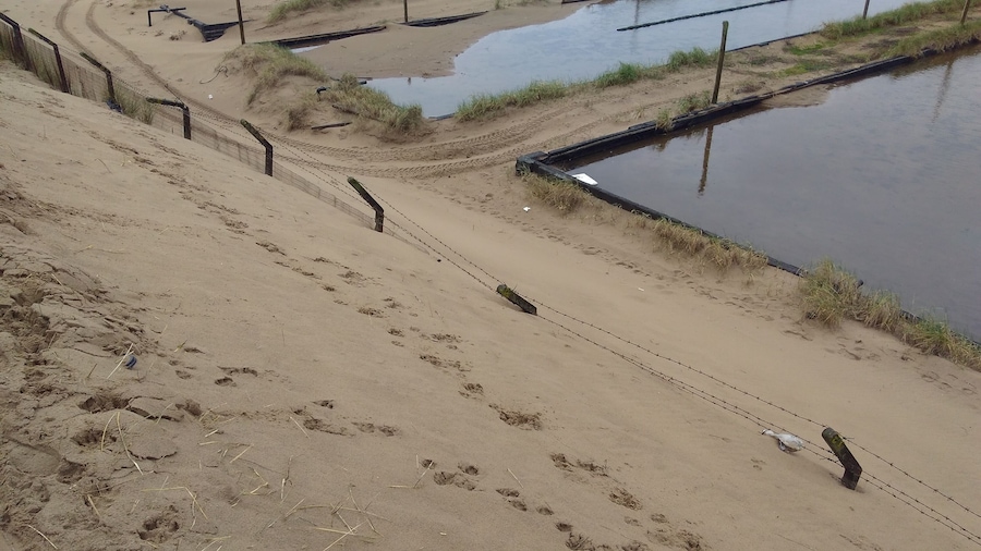Fencing nearly buried by adjoining sand dunes at the old BP chemicals site near Port Talbot in South Wales.