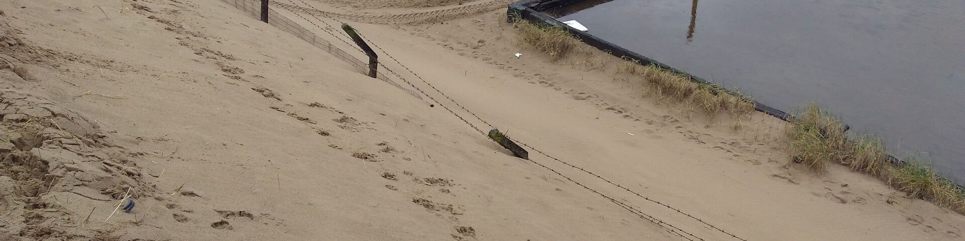 Fencing nearly buried by adjoining sand dunes at the old BP chemicals site near Port Talbot in South Wales.