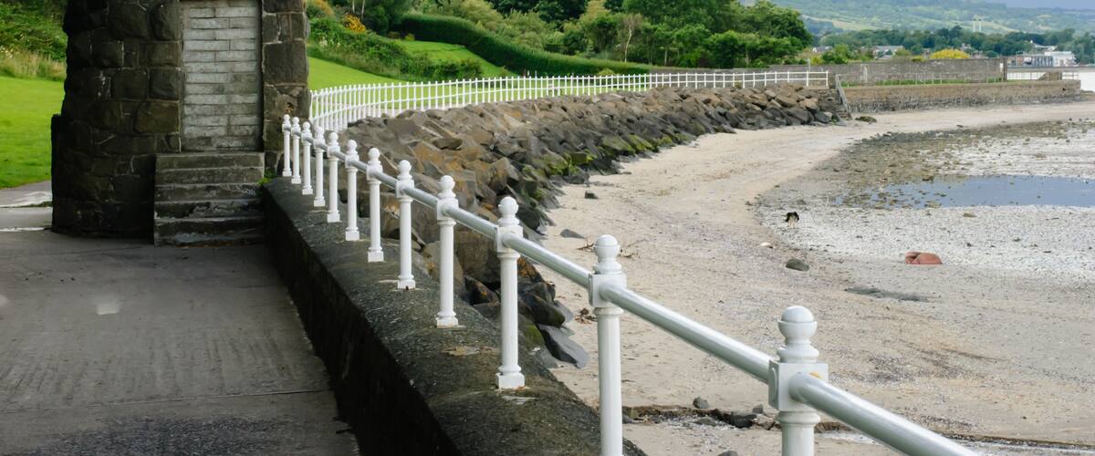 A stone structure with a white fence along a coastal path.