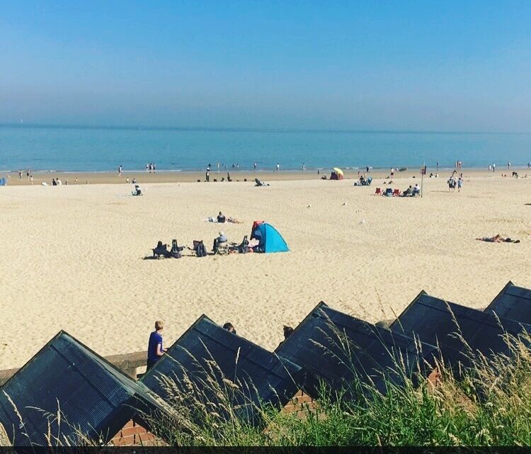 A beach with people, tents, and beach chairs.