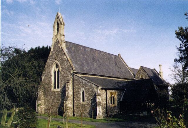 A stone church with a steeply pitched roof and a bell tower.