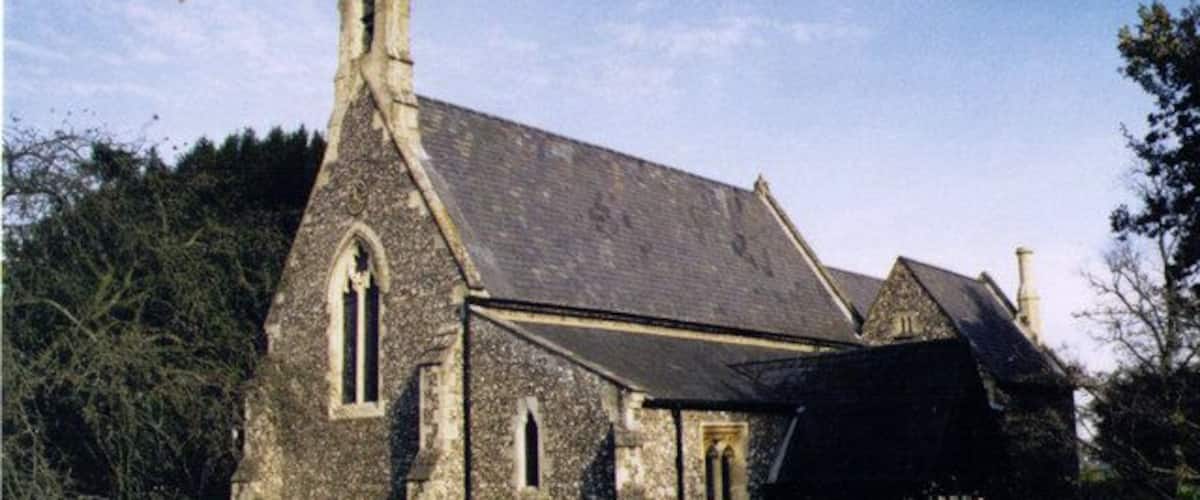 A stone church with a steeply pitched roof and a bell tower.