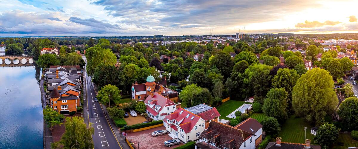 An aerial view of a town with a river, green spaces, and historic buildings.