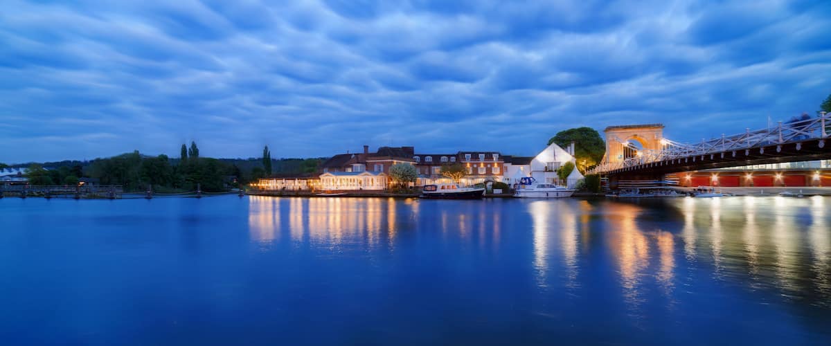 A calm river with buildings and a bridge reflecting on the water.