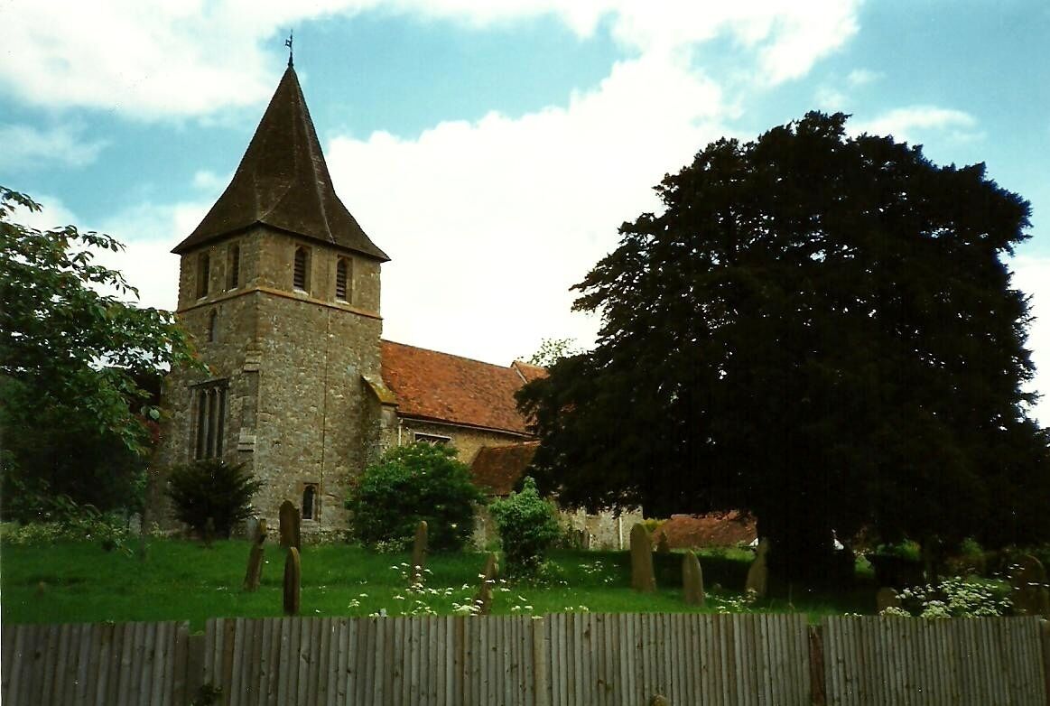 A church with a tall tower and a large tree in the foreground.