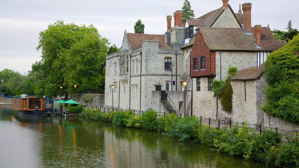 A historic stone building with a river in front.