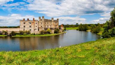 A historic castle by a calm lake surrounded by lush greenery.