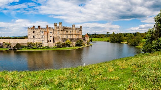 A historic castle by a calm lake surrounded by lush greenery.