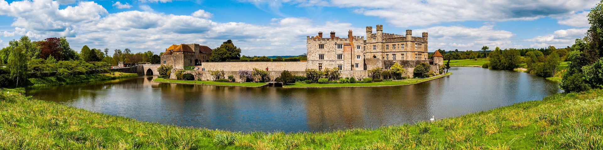 A historic castle by a calm lake surrounded by lush greenery.