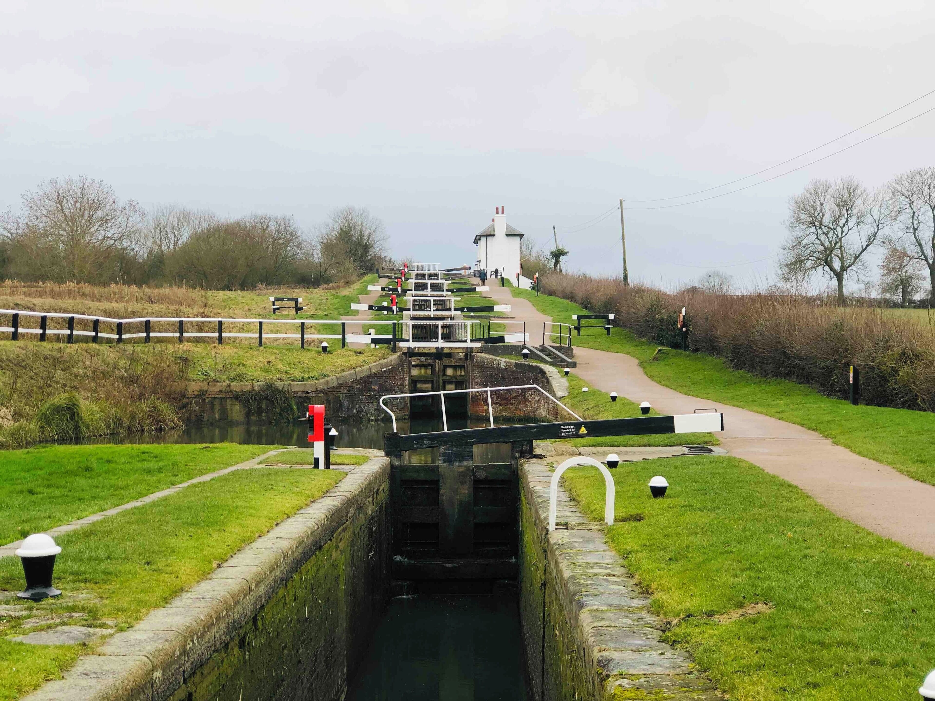 A canal lock with a pathway leading to a white building.