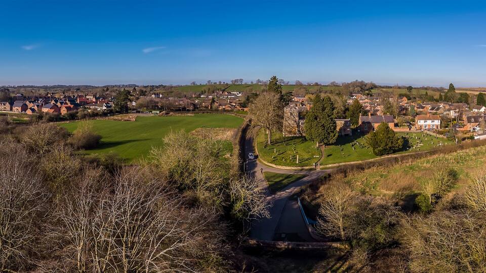 A rural landscape with a golf course, a cemetery, and residential houses.