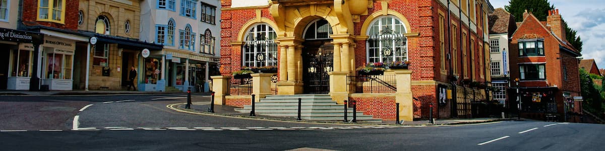 A historic building with a red roof and ornate facade, surrounded by other buildings.