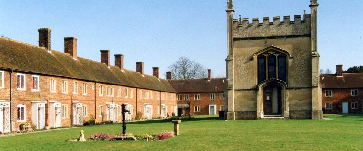 A courtyard with a large stone tower and a row of brick buildings.
