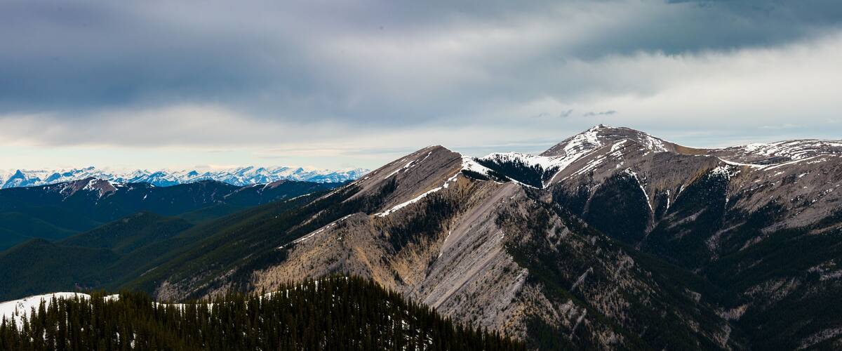 A mountain range with snow-capped peaks and dense forests.