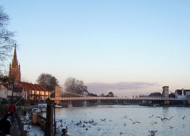 A river with a bridge, a church, and a flock of birds.