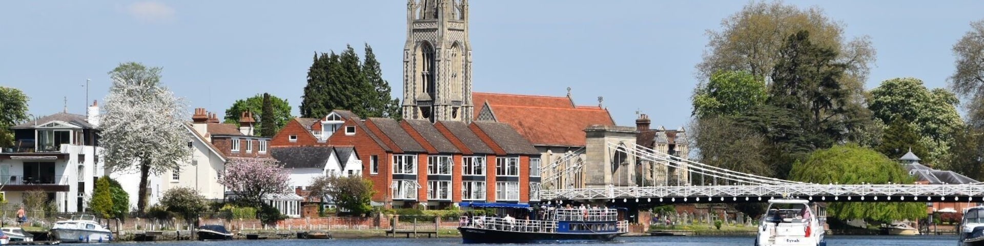 A river with boats, a bridge, and a church with a spire.