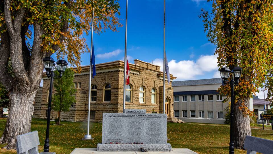 A stone building with a plaque, two benches, and a flagpole.