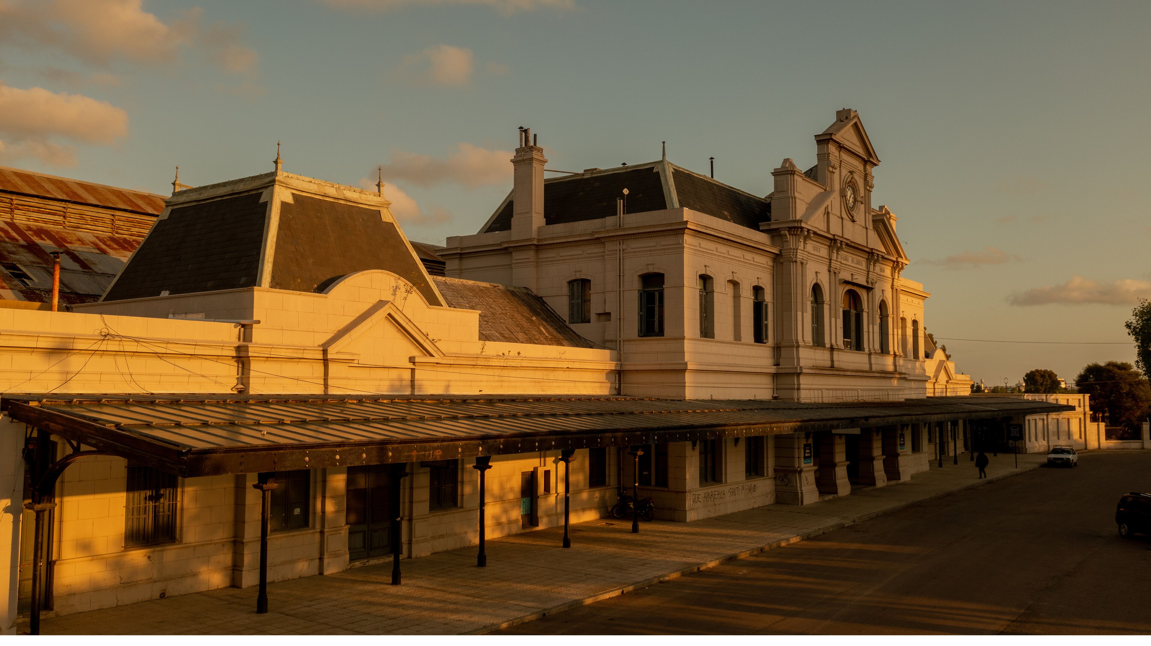 A historic building with a clock tower and a covered walkway.