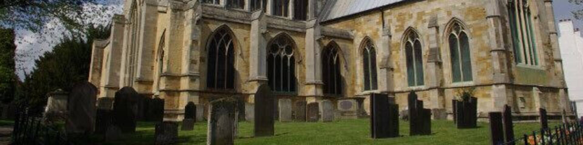 A historic church with a tall tower, arched windows, and a well-maintained lawn.