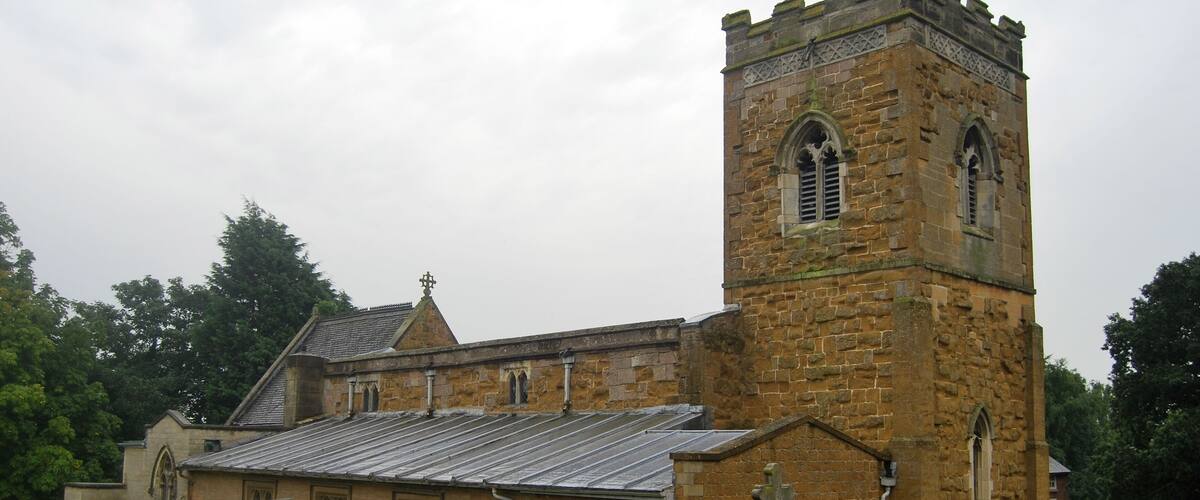 A church with a tall tower and multiple tombstones in the foreground.