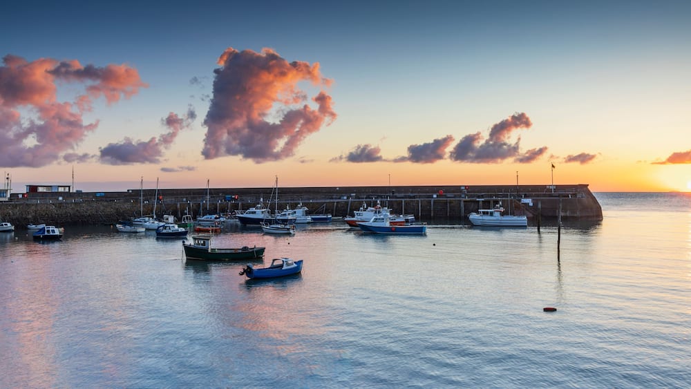 Ein Hafen bei Sonnenuntergang mit vertäuten Booten und einer anlegenden Pier.