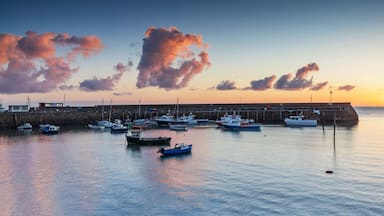 Un puerto al atardecer con barcos amarrados y un muelle que se adentra en el agua.