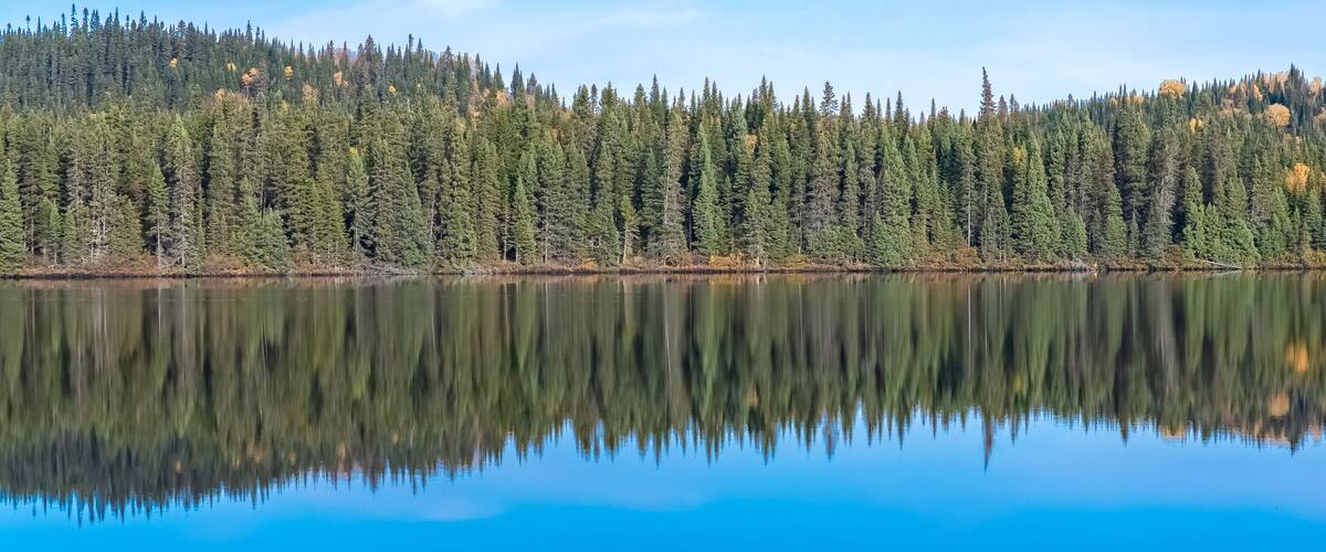 Canada, panorama of a mountain lake in the forest during the Indian summer, beautiful landscape in a wild country, reflection on the water