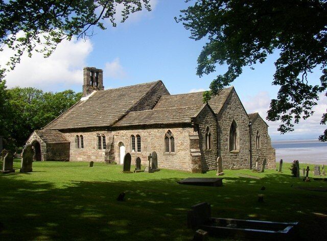 A historic stone church with a grassy cemetery in front.