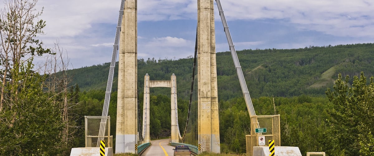 A large concrete bridge with a single vehicle on the road.