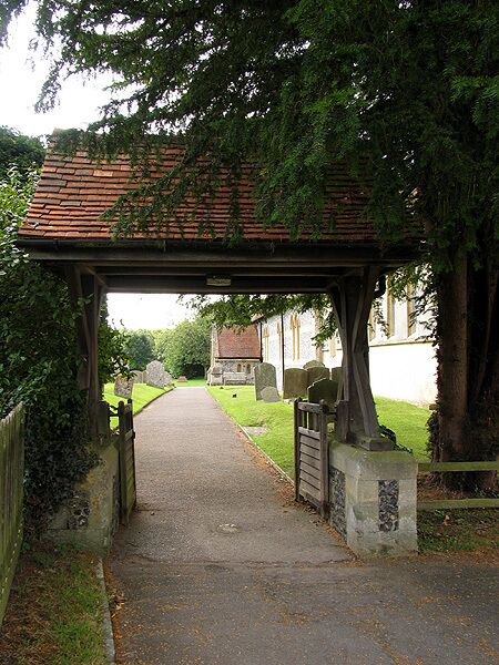 A pathway leading to a cemetery under a covered archway.