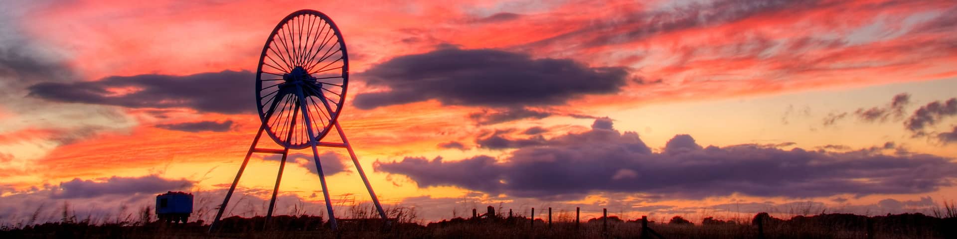 A windmill silhouetted against a vibrant sunset sky.
