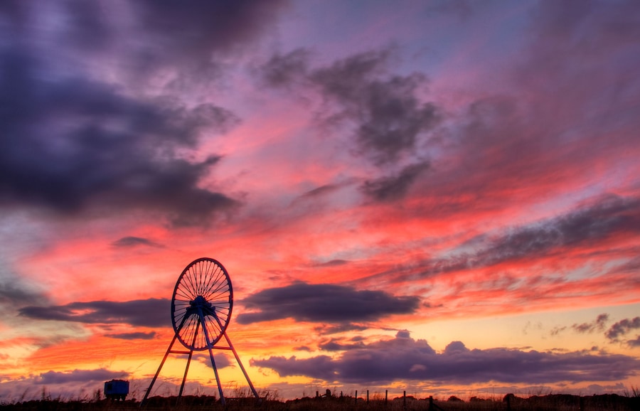 A windmill silhouetted against a vibrant sunset sky.