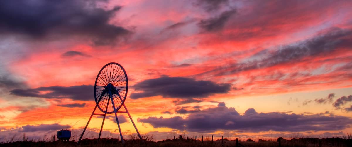 A windmill silhouetted against a vibrant sunset sky.