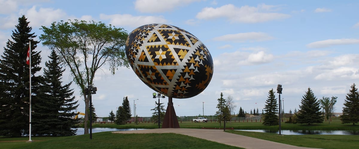 A large decorative sphere with star patterns in a park with trees and a pathway.
