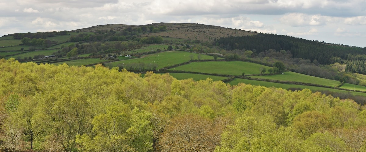 Rolling hills, green fields, and a cloudy sky.