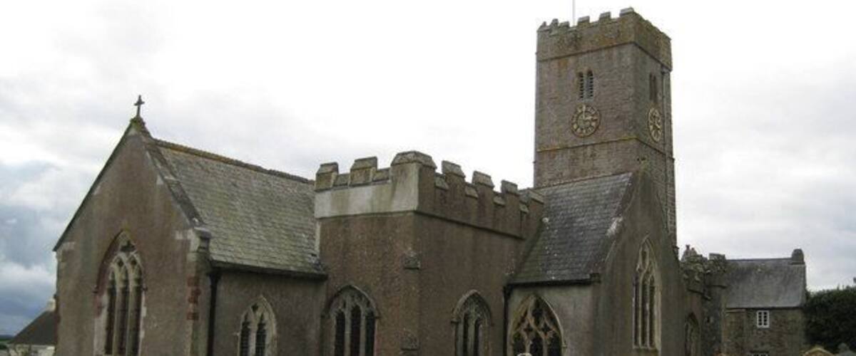 A historic church with a tall tower and a graveyard in front.