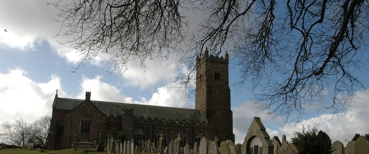 A church with a tall tower and a graveyard with numerous headstones.
