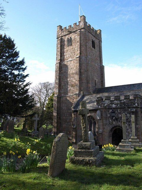 A stone church with a tower and a graveyard with headstones.