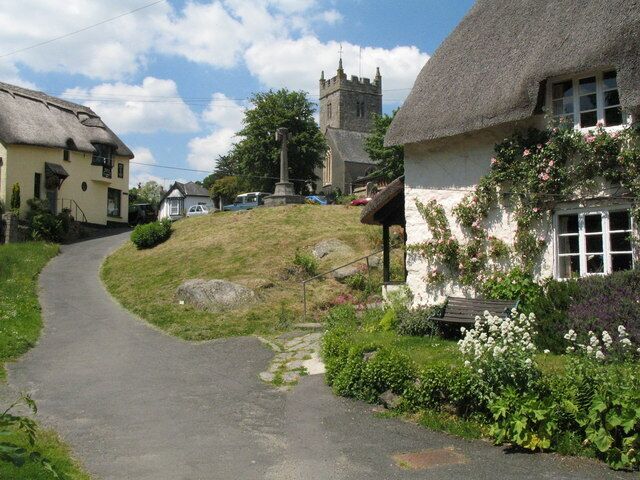 Lustleigh Village Green The green is quite small and contains the war memorial. The church is in the distance. The lane leads down (behind the photographer) to a small stream which runs under the disused rail bridge and on by the cricket field to Wreyland. The Primrose Cafe is on the left of the photograph.