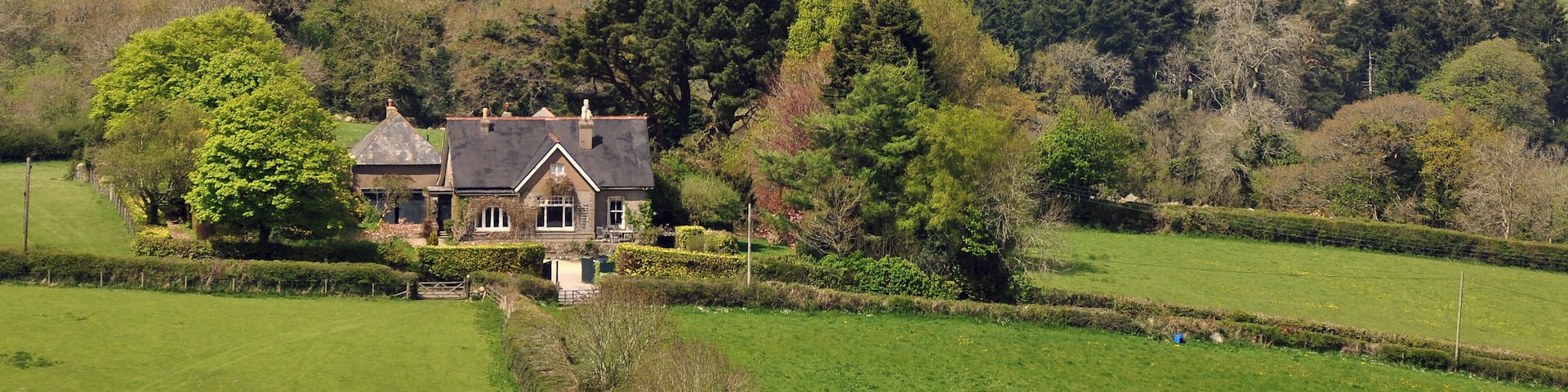 A rural landscape with rolling hills, scattered houses, and a prominent manor house.